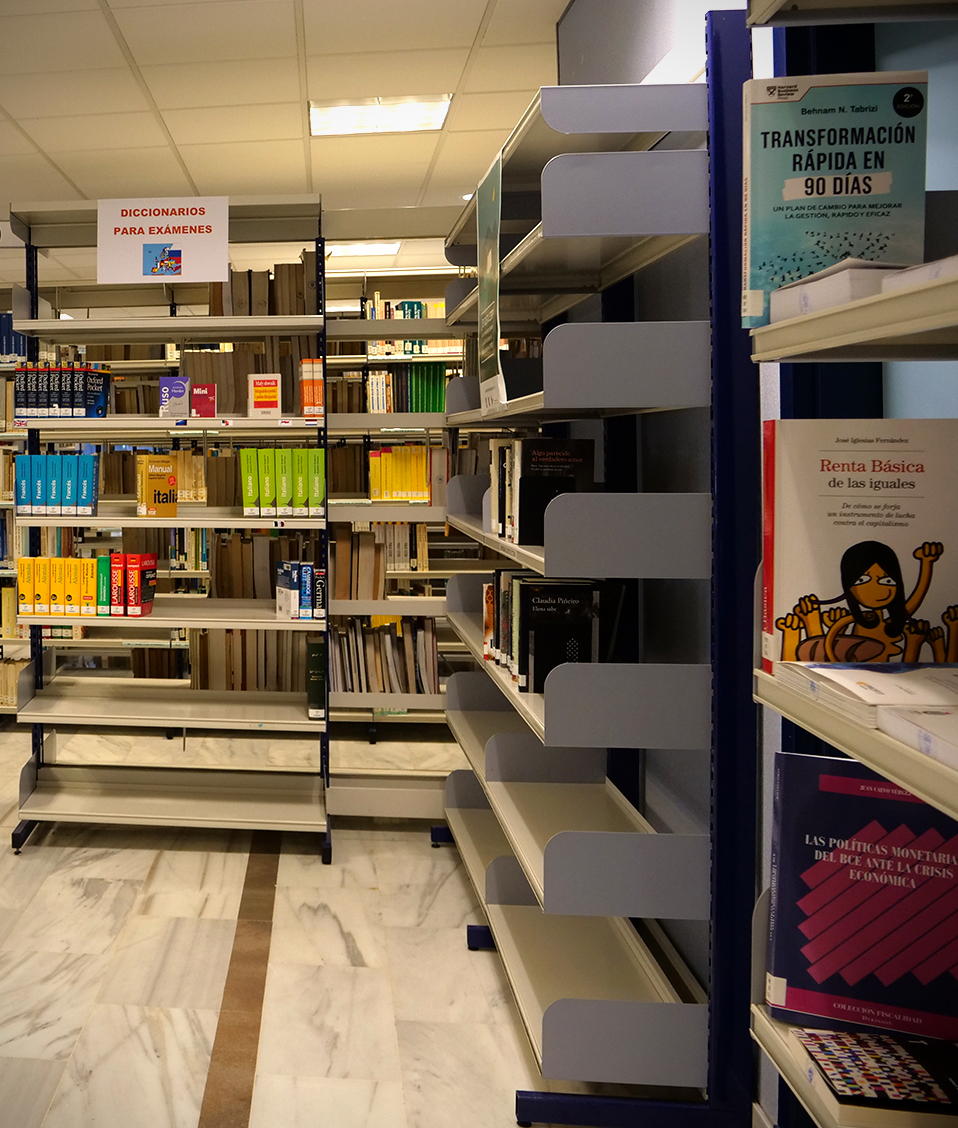 Biblioteca de la Facultad de Ciencias Económicas y Empresariales de Granada. Podemos ver dos estudiantes buscando algún libro en las estanterías